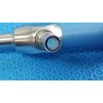Silver ideal eyes 10mm surgical instrument with blue-tinted lens tip resting on textured blue surface