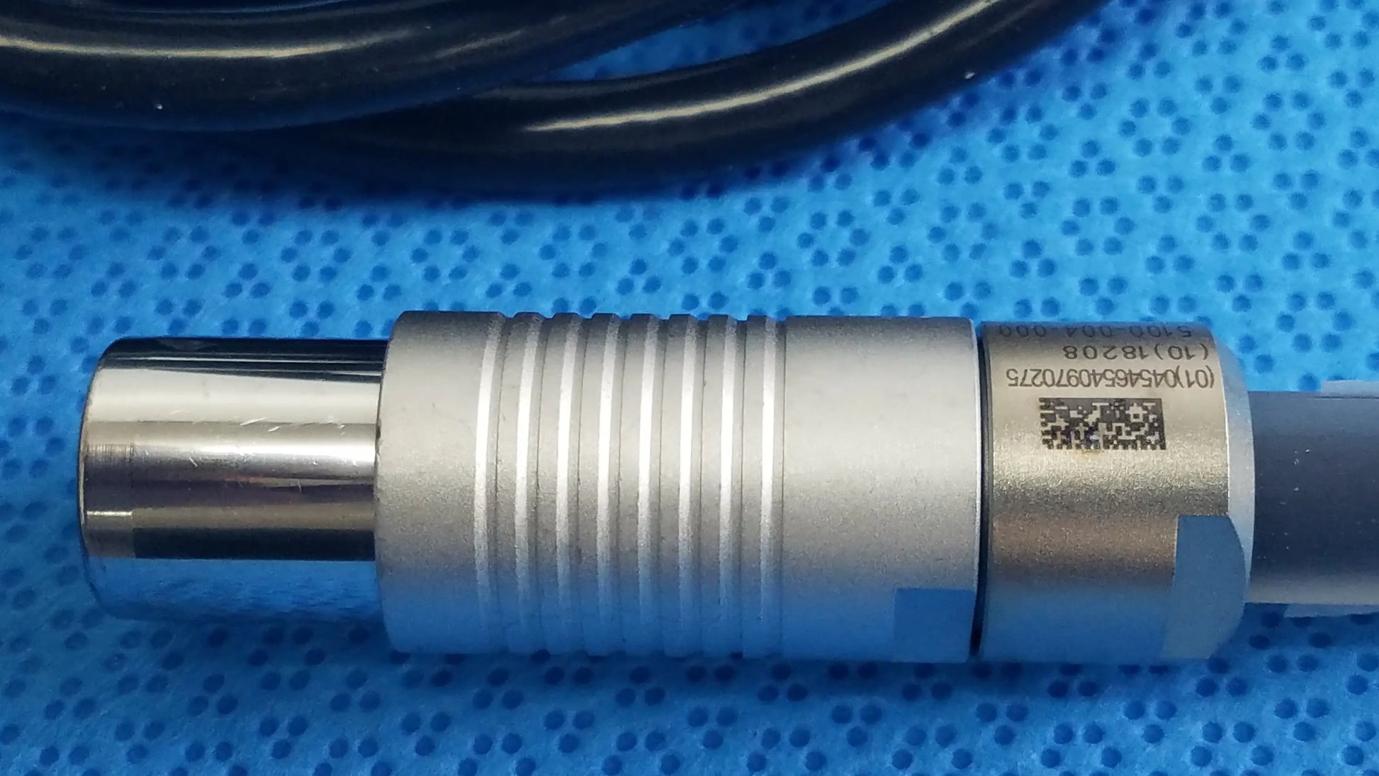 Silver metallic cylindrical sensor with ridged texture and qr code label on the back of stryker 5100-004-000 scher handpiece cable for reuse medical equipment