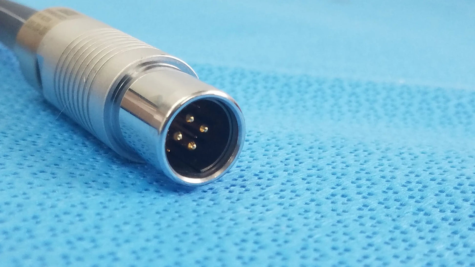 Silver metallic connector with threaded housing and four gold-plated pins for reuse medical equipment scher handpiece cable