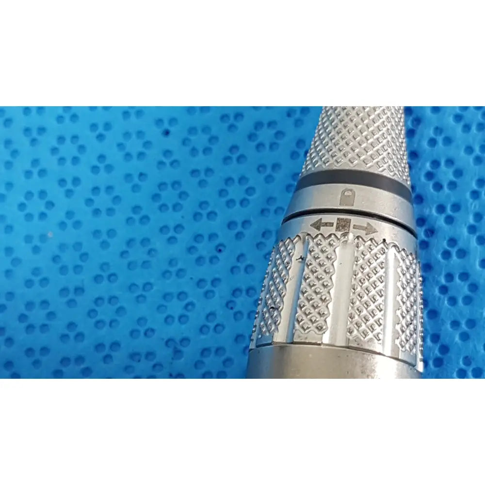 Silver-colored metal surgical power tool handle with textured diamond grip and engraved directional arrows maestro attachment