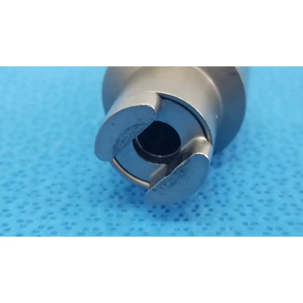 Silver-colored metallic cylindrical hudson modified trinkle with central hole and three curved flanges for reuse medical use