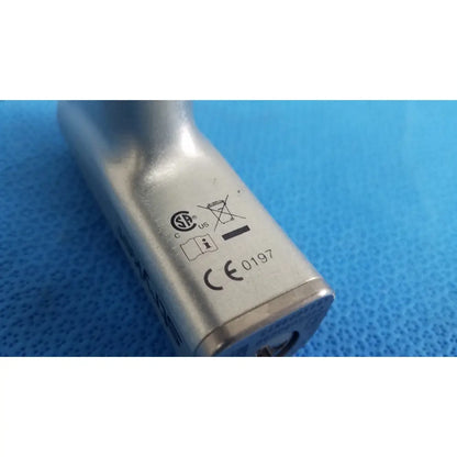 Silver metallic stryker cd4 cordless driver adapter with embossed certification marks and a keyhole on its side