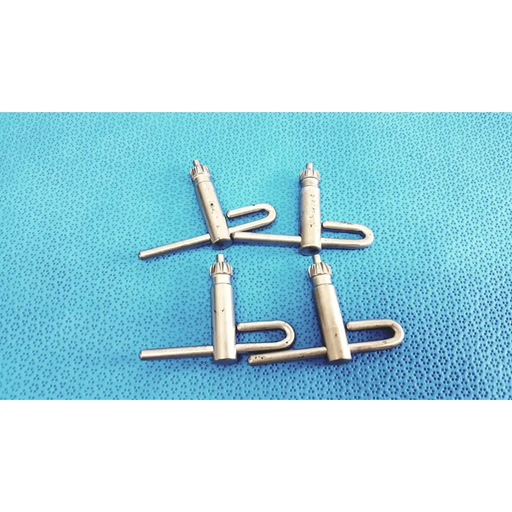 Four metallic silver stryker chuck keys with cylindrical body u-shaped handle and threaded top for surgical drills