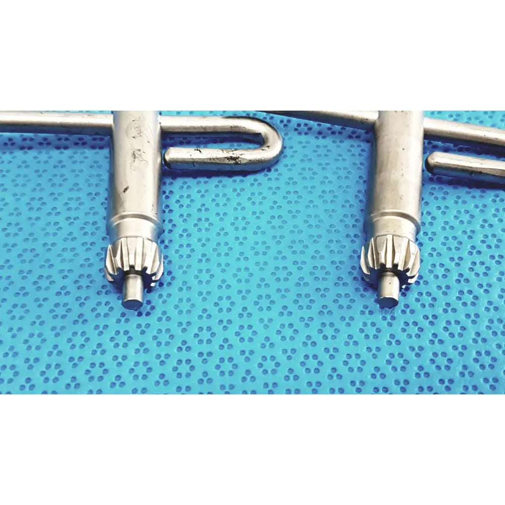 Silver surgical drill bits with gear-like tips resting on blue perforated surface for stryker chuck key lot of 4