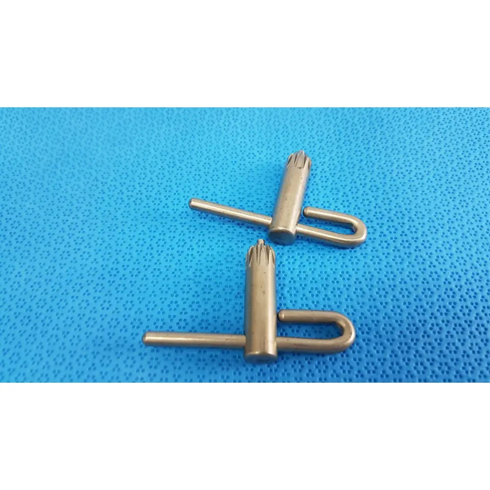 Two brass-colored metal stryker chuck keys with u-shaped handle and star-like multi-pointed tip for surgical drills