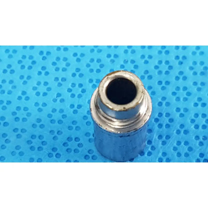 Silver metallic cylindrical stryker light post adapter with threaded interior and worn edges for fiber optic cables