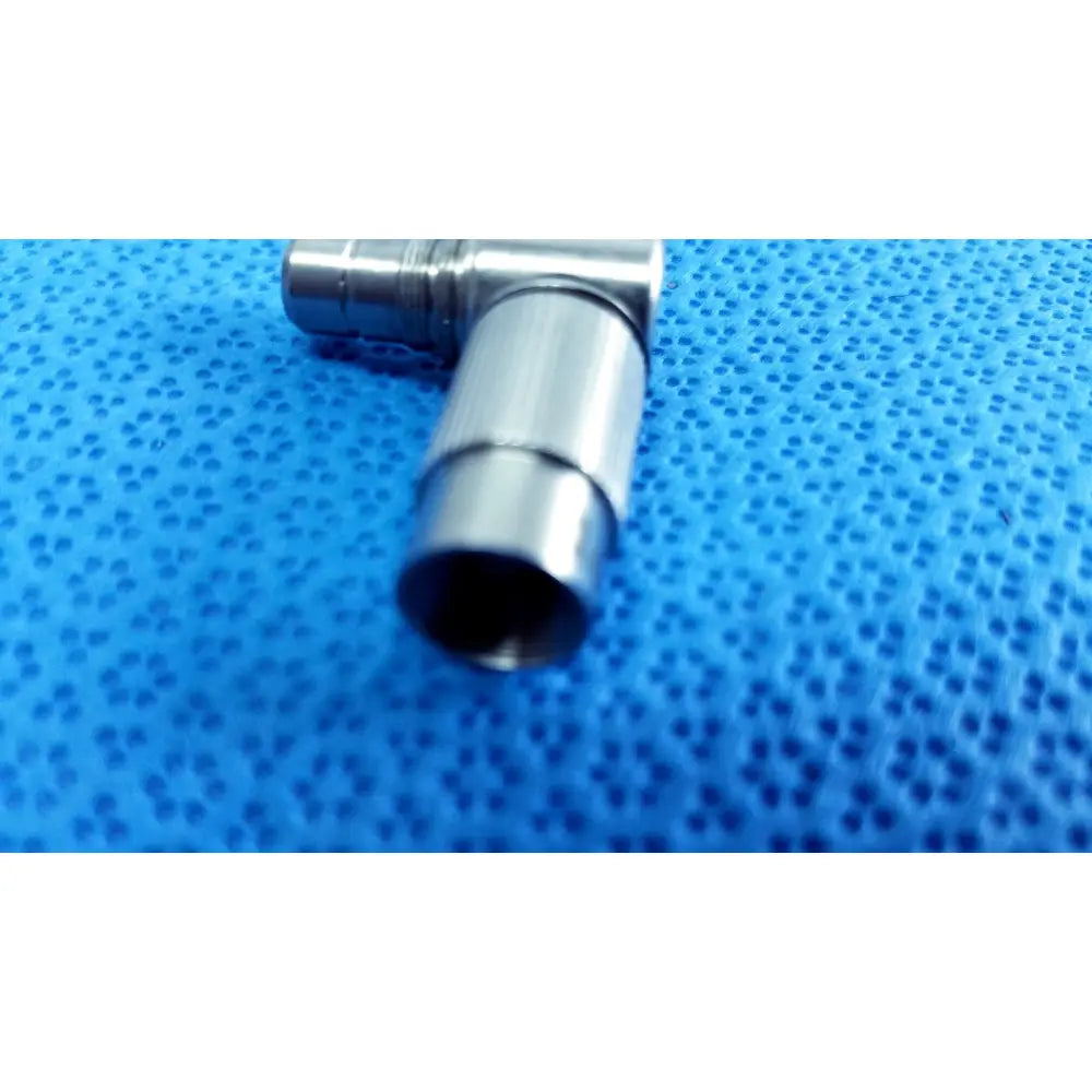 Silver-colored metal t-shaped connector from stryker lot autoclavable 10mm 134ºc scope with polished reflective surface