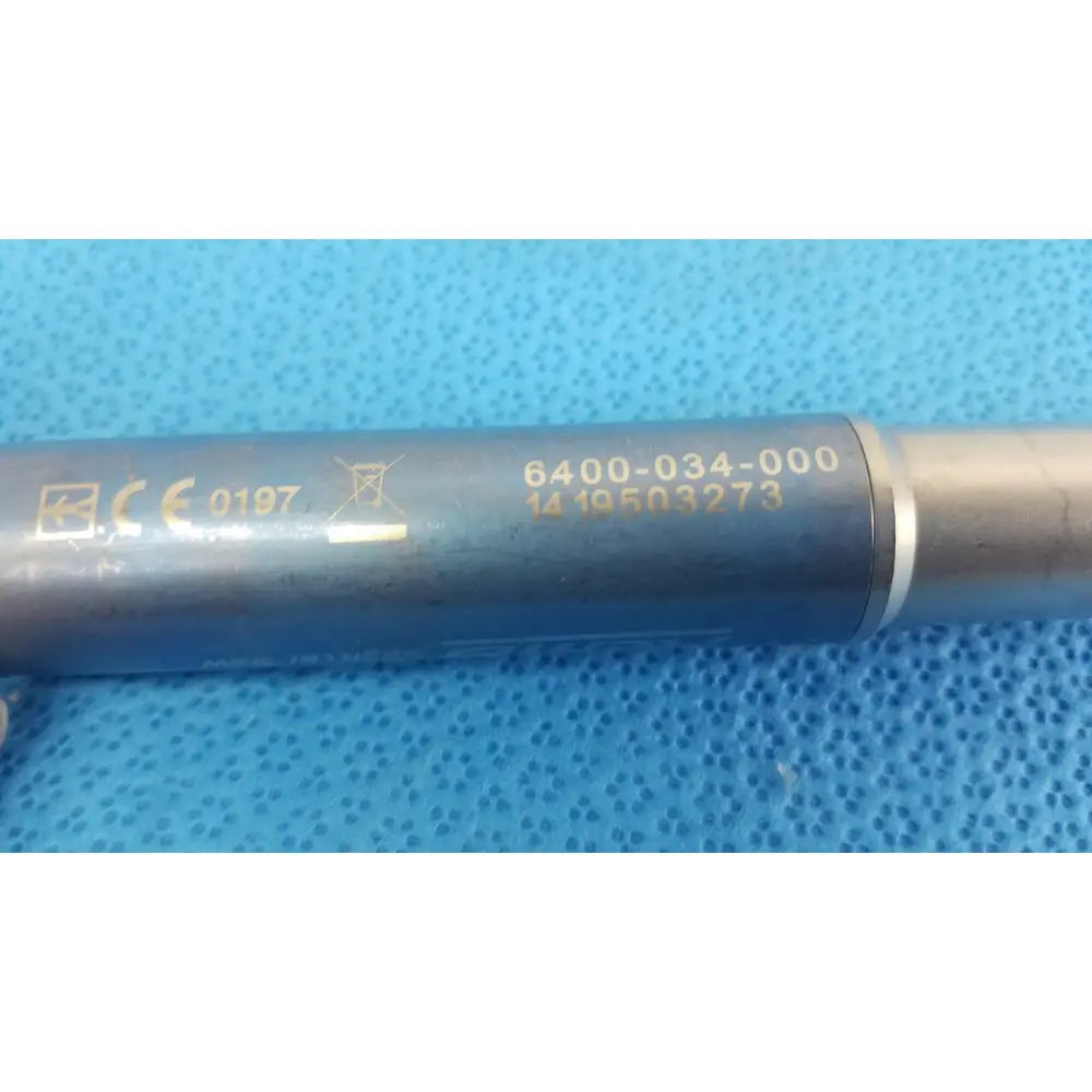 Gray cylindrical metal rod with engraved markings and silver band part of stryker remb electric sagittal saw