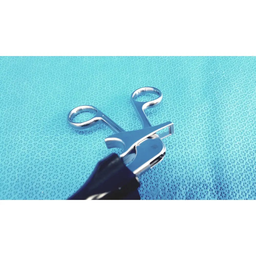 Stryker stainless steel laparoscopiic clamp with black rubberized handles resting on blue textured surface