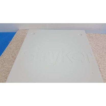 White rectangular plastic plate with embossed shinykey logo and mounting holes for stryker suitestream hd medical integration system