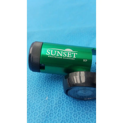 Green metallic sunset brass integral 50 psi min o2 regulator with black textured cap featuring sunset healthcare solutions branding