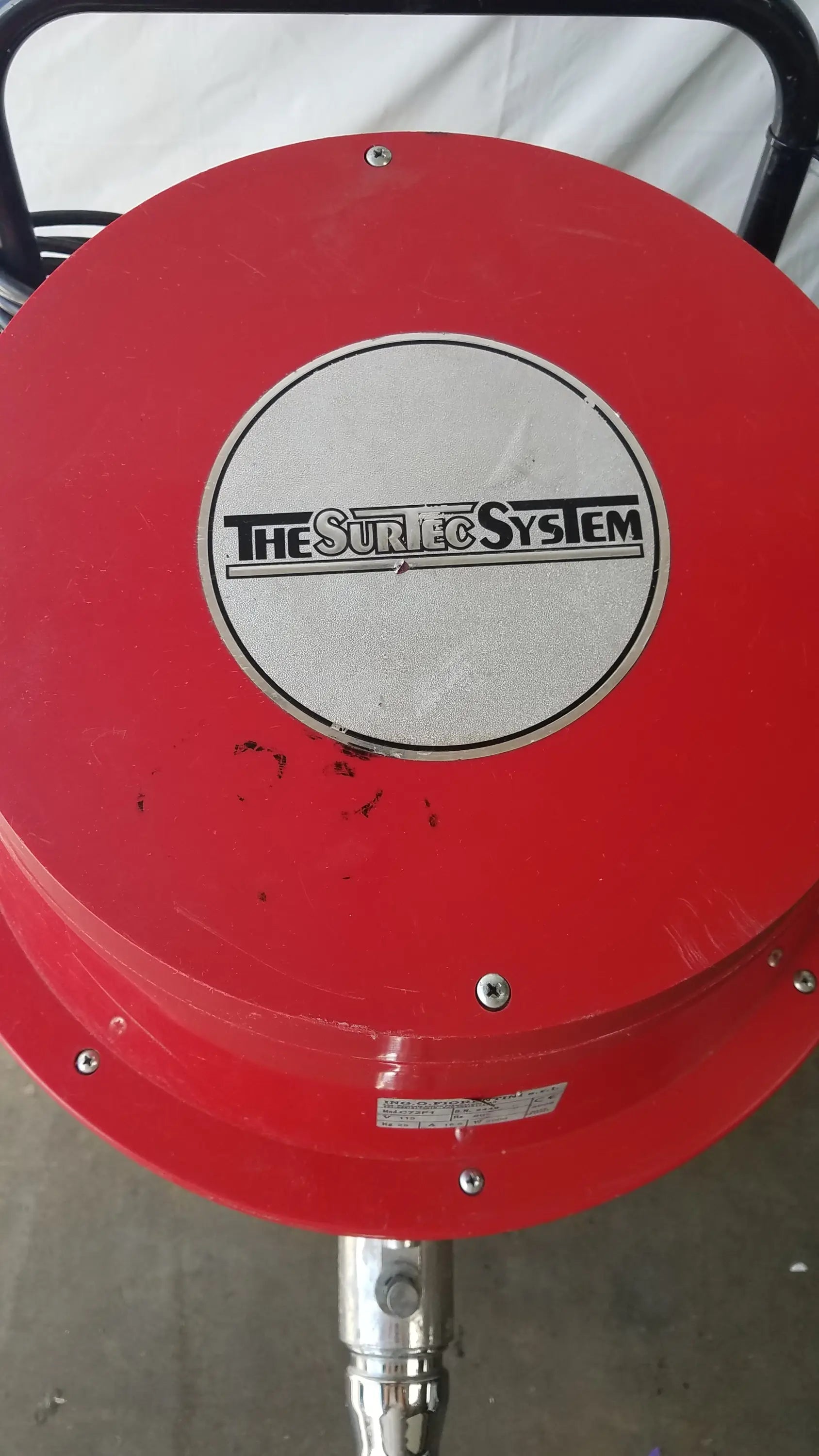 Red circular industrial housing with silver the surfec system logo plate and metallic fittings for wet dry vacuum