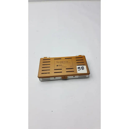 Bronze-colored metal synovis gem precision instrument case with ventilation slits and white label number 58