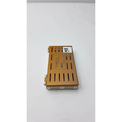 Gold-colored metal synovis gem precision surgical instrument case with hinged lid and ventilation slits for microtray organization
