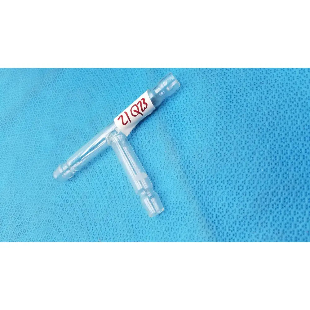 Clear plastic t-shaped hose connector tube 71mm with a white label marked 21qz3 in red ink for labware use