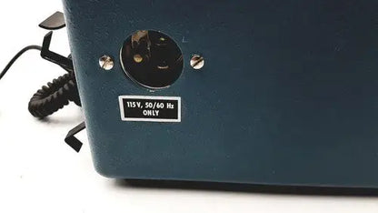 Dark teal plastic power input port with black coiled cord and silver screws on the back of teledyne portable oxygen analyzer