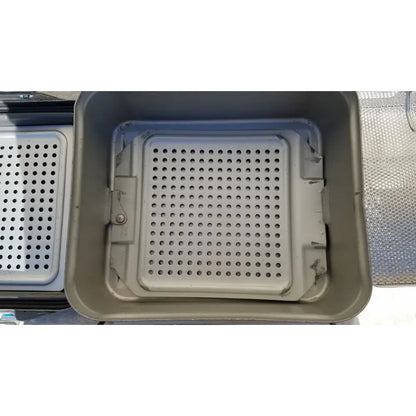 Gray plastic baking tray with perforated insert in the case genesis sterilization container with basket for medical use
