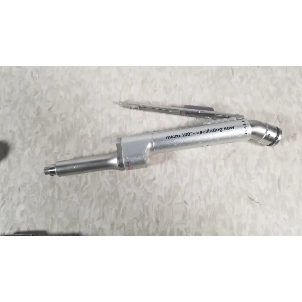 Silver metallic micro 100 oscillating saw with curved handle and engraved branding from the case genuis serial no 9354 patent pending