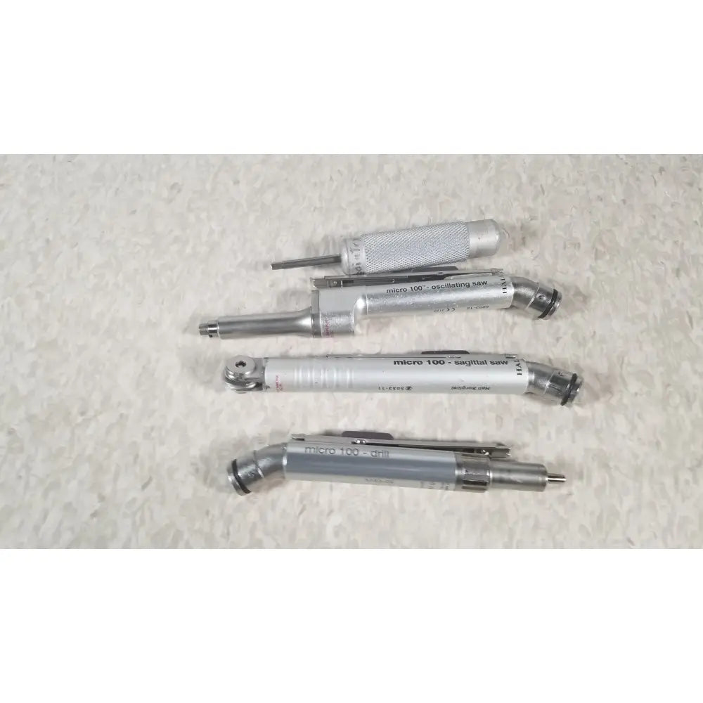 Set of four silver-colored micro 100 precision tools including oscillating saw sagittal saw and drill in case genuis serial no 9354