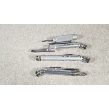 Set of four silver-colored micro 100 precision tools including oscillating saw sagittal saw and drill in case genuis serial no 9354