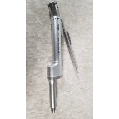 Silver metal oscillating saw with cylindrical body engraved micro 100 model from the case genuis serial no 9354 patent pending