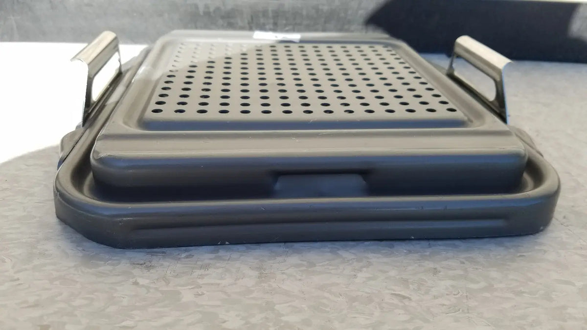 Black plastic folding grill with perforated surface and metallic handles for case sterilization container half lid use