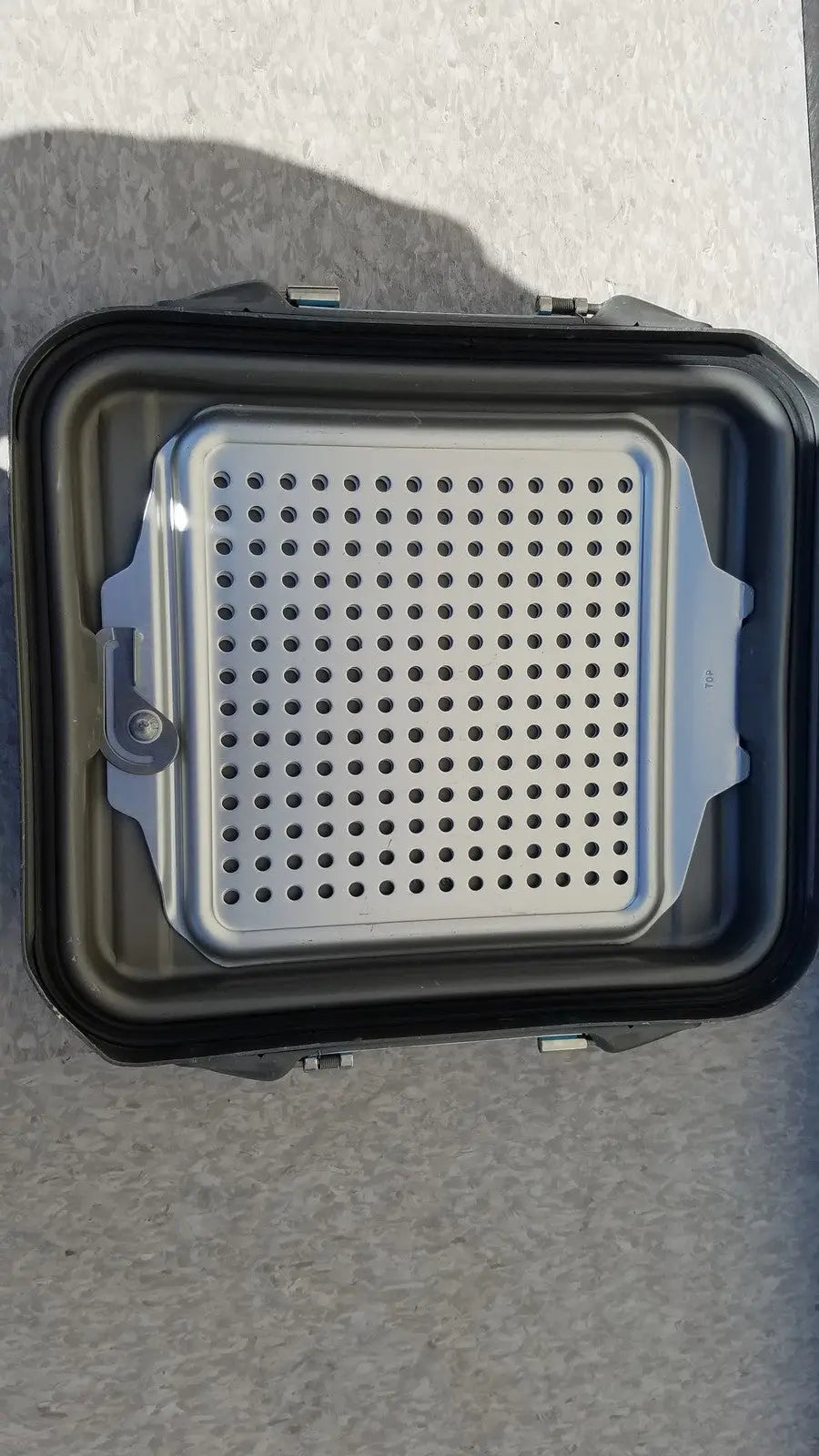 Black plastic case sterilization container half with silver perforated metal grilling tray and container half lid