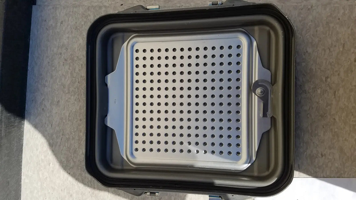 Silver perforated metal grilling plate with reinforced edges for case sterilization container half lid black
