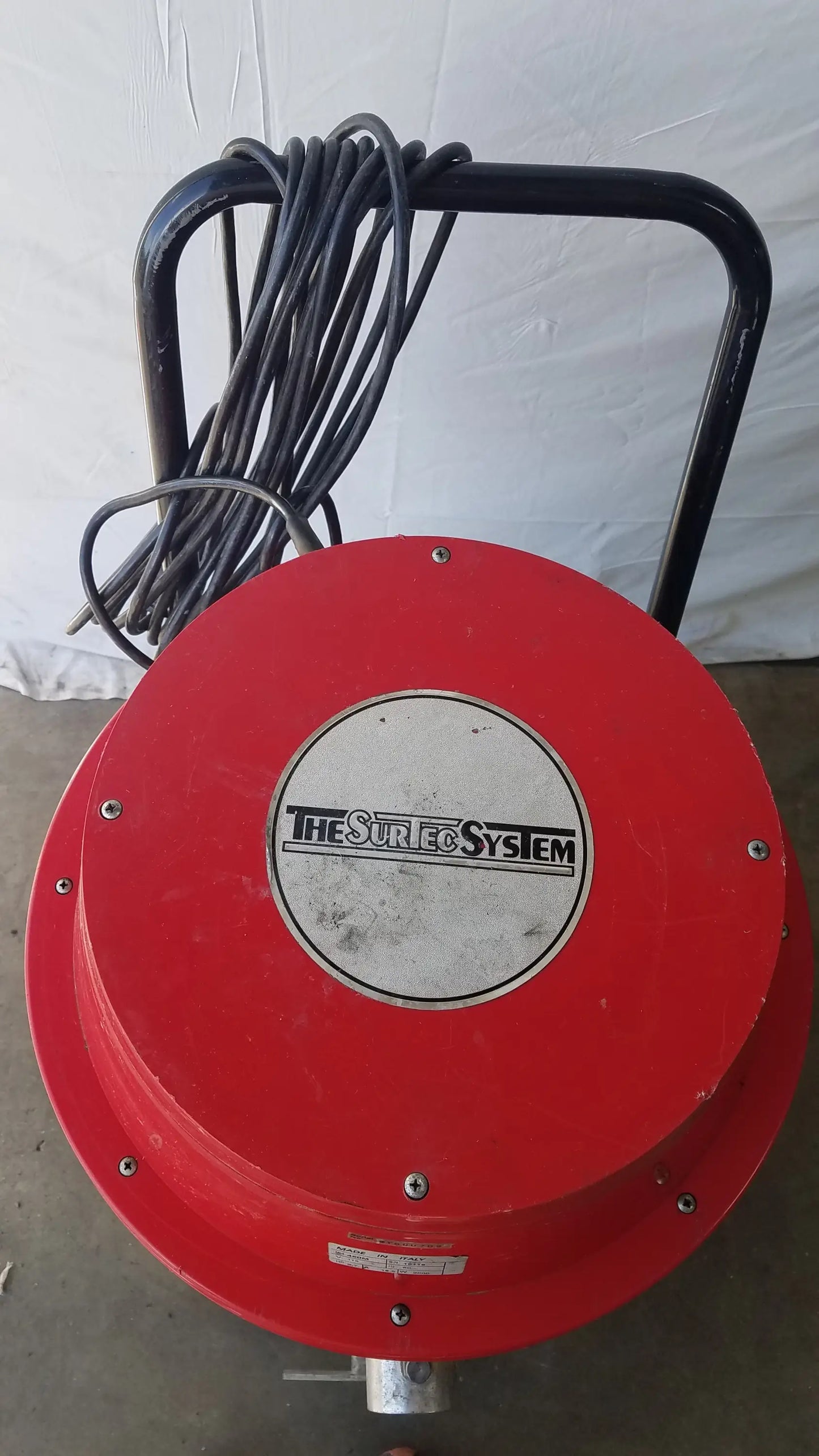 Red circular wet dry drum vacuum cleaner with black handle and coiled cord branded the surfco system on silver label