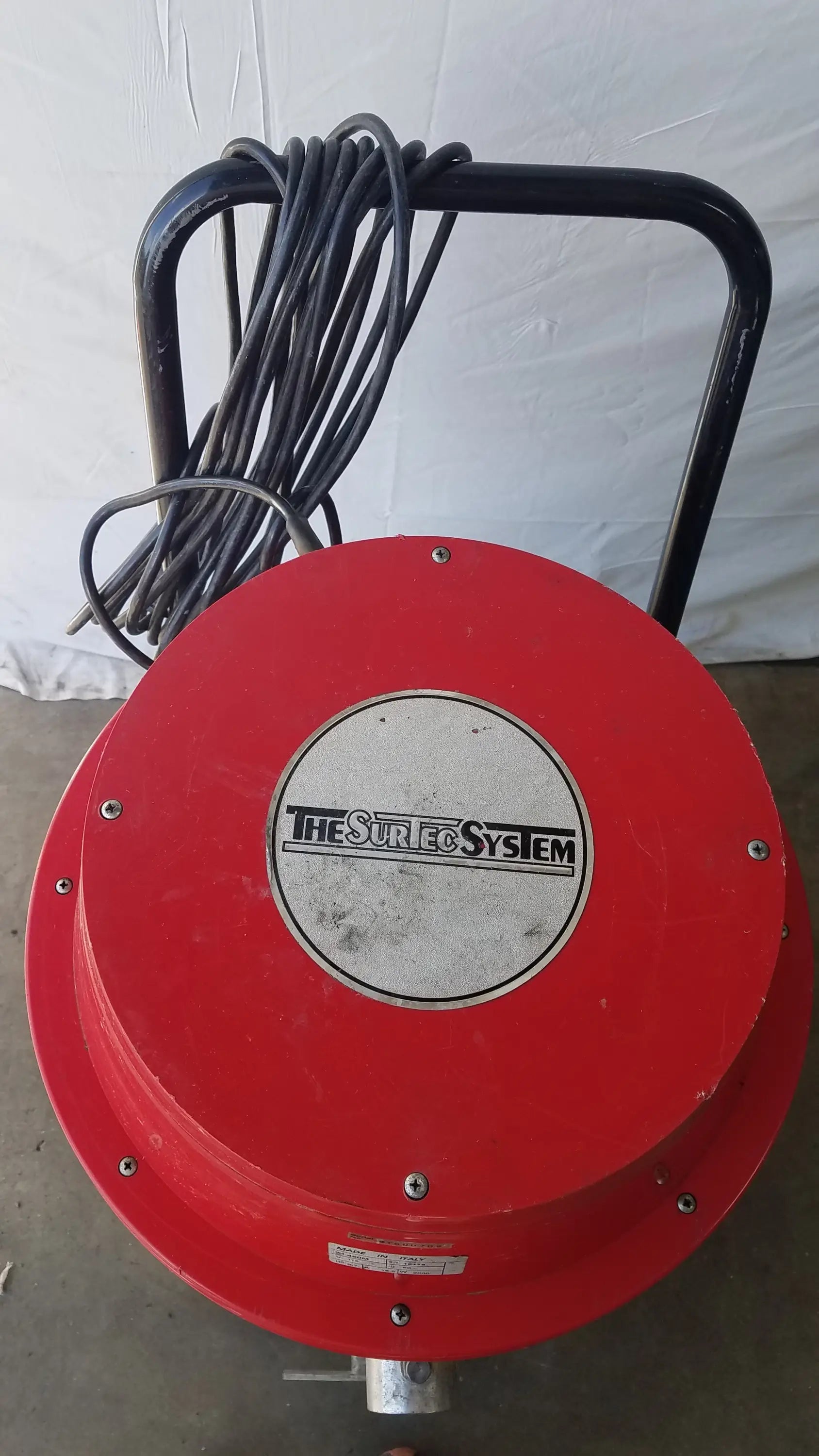 Red circular wet dry drum vacuum cleaner with black handle and coiled cord branded the surfco system on silver label