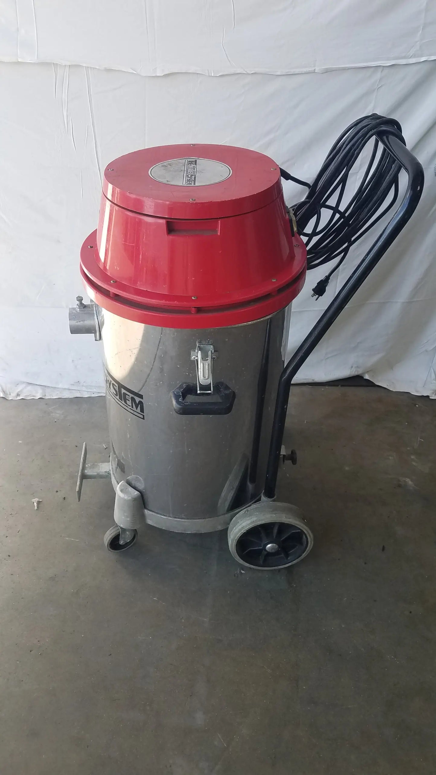 The Surtec System 450M red and silver wet dry drum vacuum cleaner with black handle and wheels for industrial use