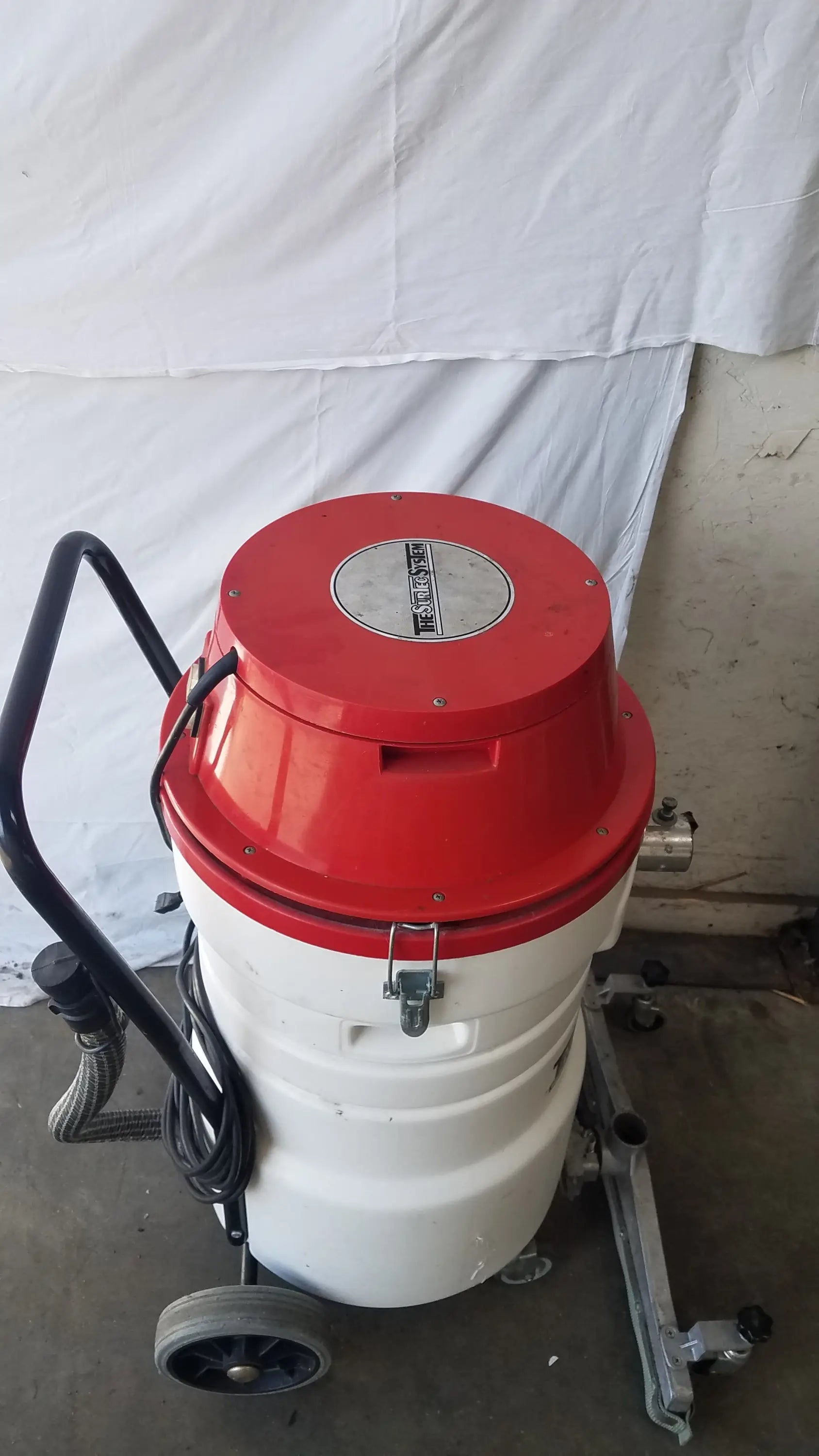 The Surtec System C72F1 wet dry vacuum cleaner 115V with red and white cylindrical body, black handle, and wheels