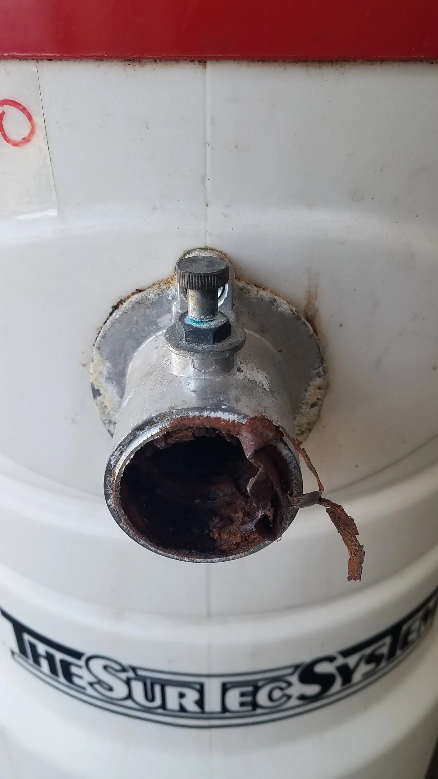 White cylindrical wet dry vacuum tank with rusted pipe and knob featuring the surtec system branding back side view