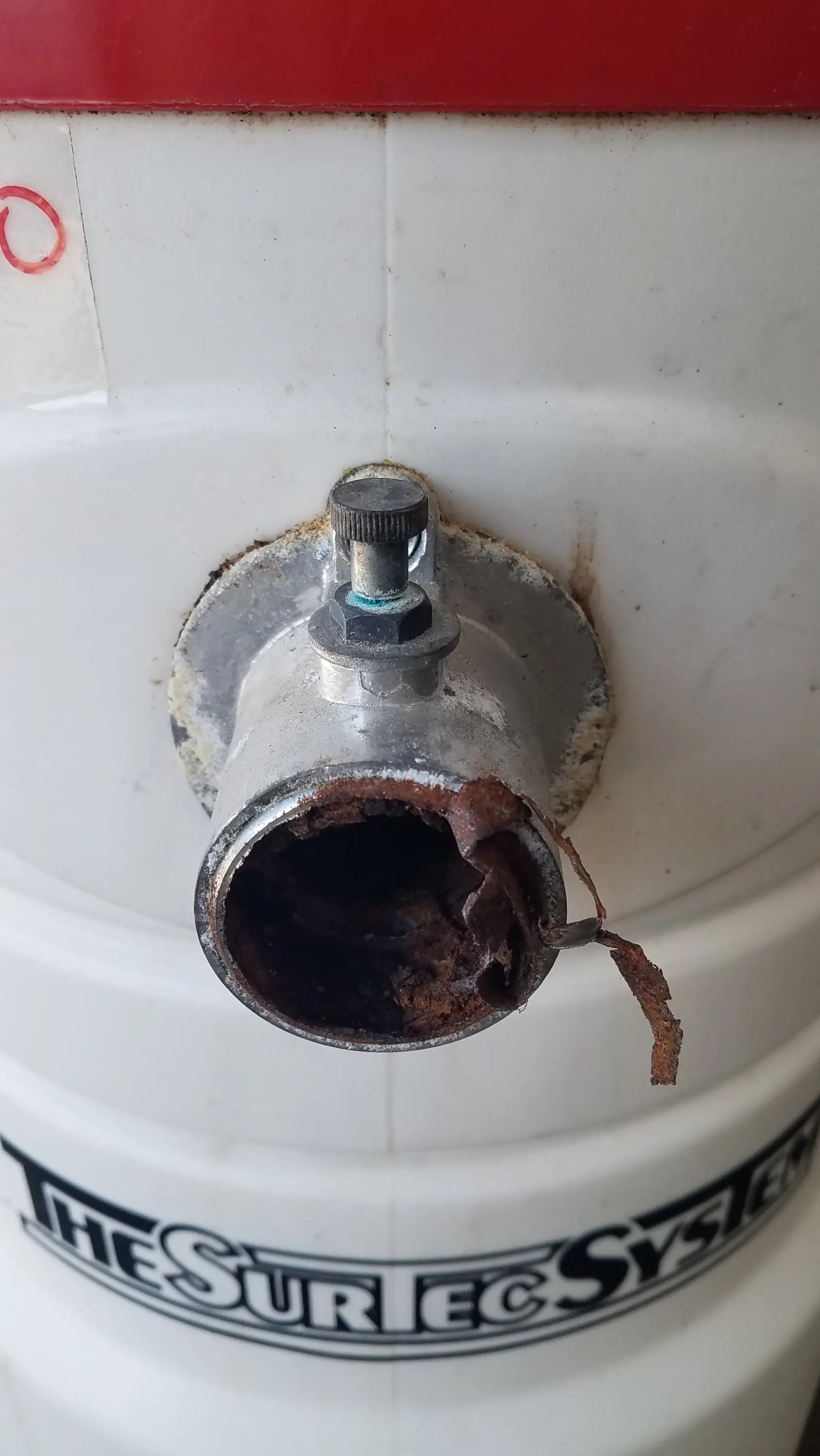 White cylindrical wet dry vacuum tank with rusted pipe and knob featuring the surtec system branding back side view