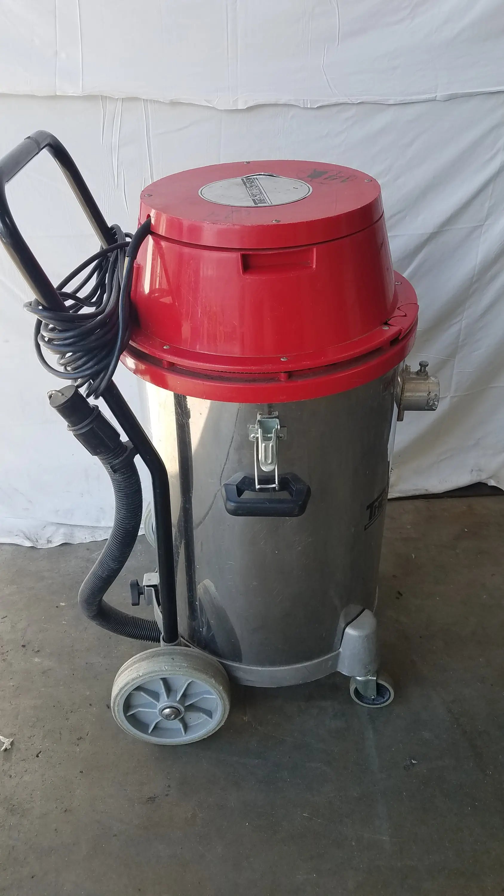 The Surtec System F46F red and gray wet dry drum vacuum cleaner with black handle and two small wheels