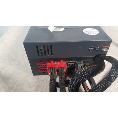 Rear view of black thermaltake 1350w toughpower gf3 power supply with red and black cables connected to ports