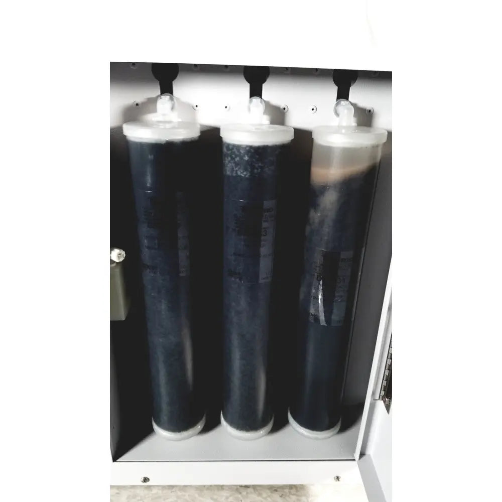 Three cylindrical water filtration cartridges with dark contents and white caps in a metallic housing of thermo scientific easypure ii d7401 lab grade system