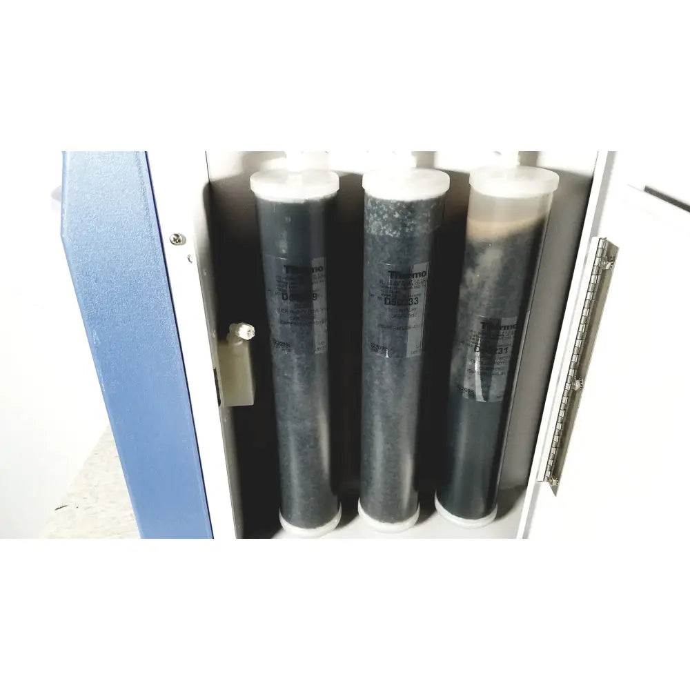 Three cylindrical thermo scientific easypure ii d7401 filter cartridges with white caps and gray granular interior