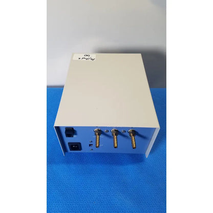 Beige and blue thermo scientific gas guard model 3050 with three gold-colored connectors on the side of the device