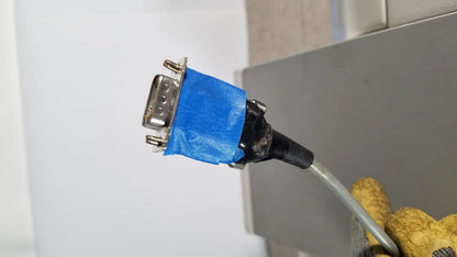 A blue-taped db9 serial connector with metallic pins and black cable on the back side of thermo scientific microm hm 340e