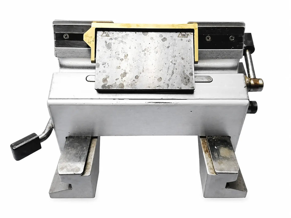 Industrial-grade metal bench vise with brass accents on a worn steel plate for thermo scientific microm hm 355s rotary microtome