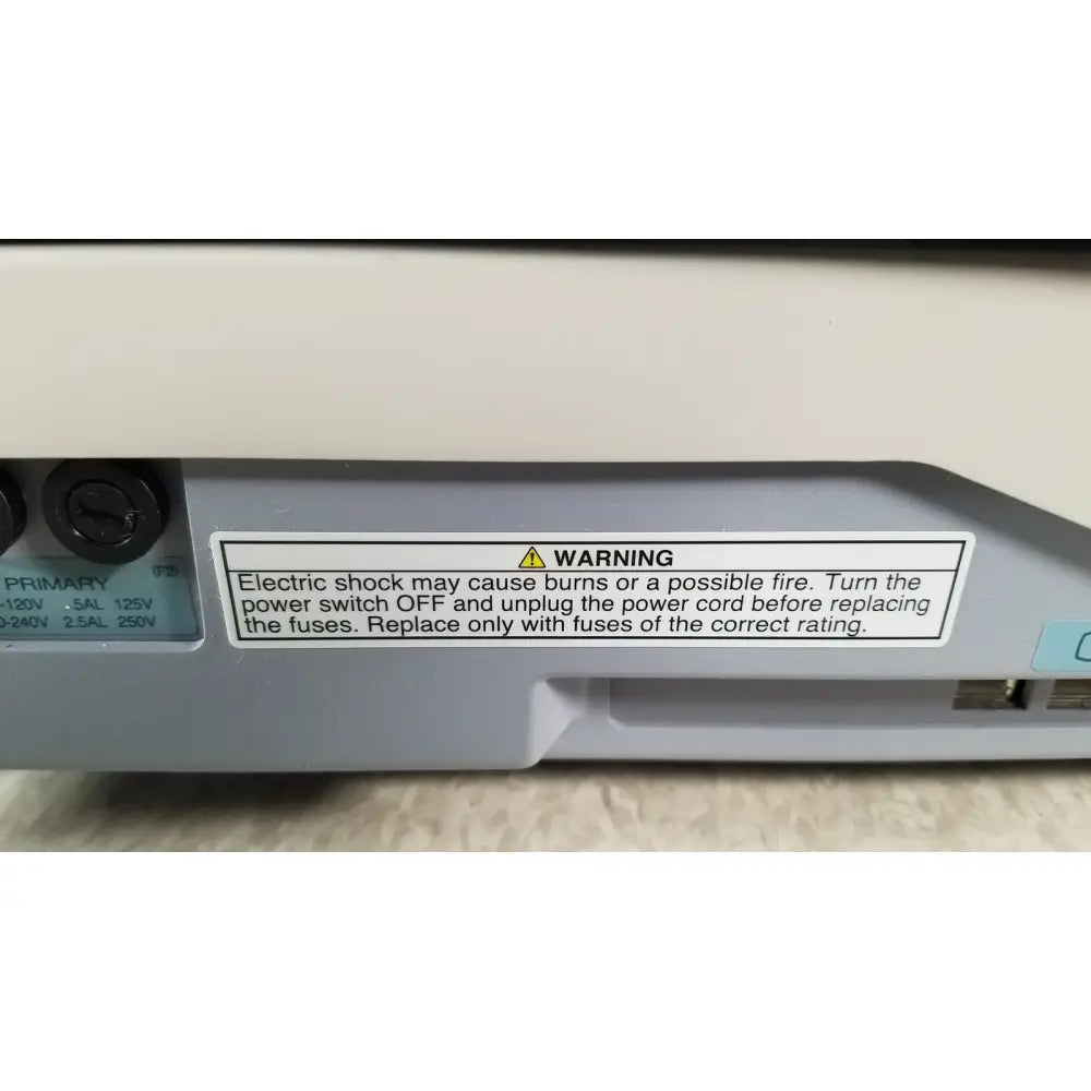 Gray plastic power supply unit with white warning label and two black input ports on back side of tracey itrace visual wsl524m