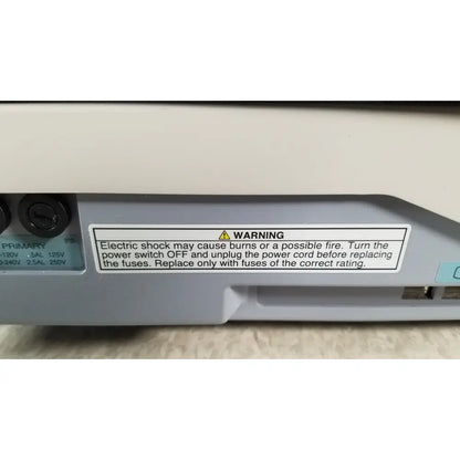 Gray plastic power supply unit with white warning label and two black input ports on back side of tracey itrace visual wsl524m