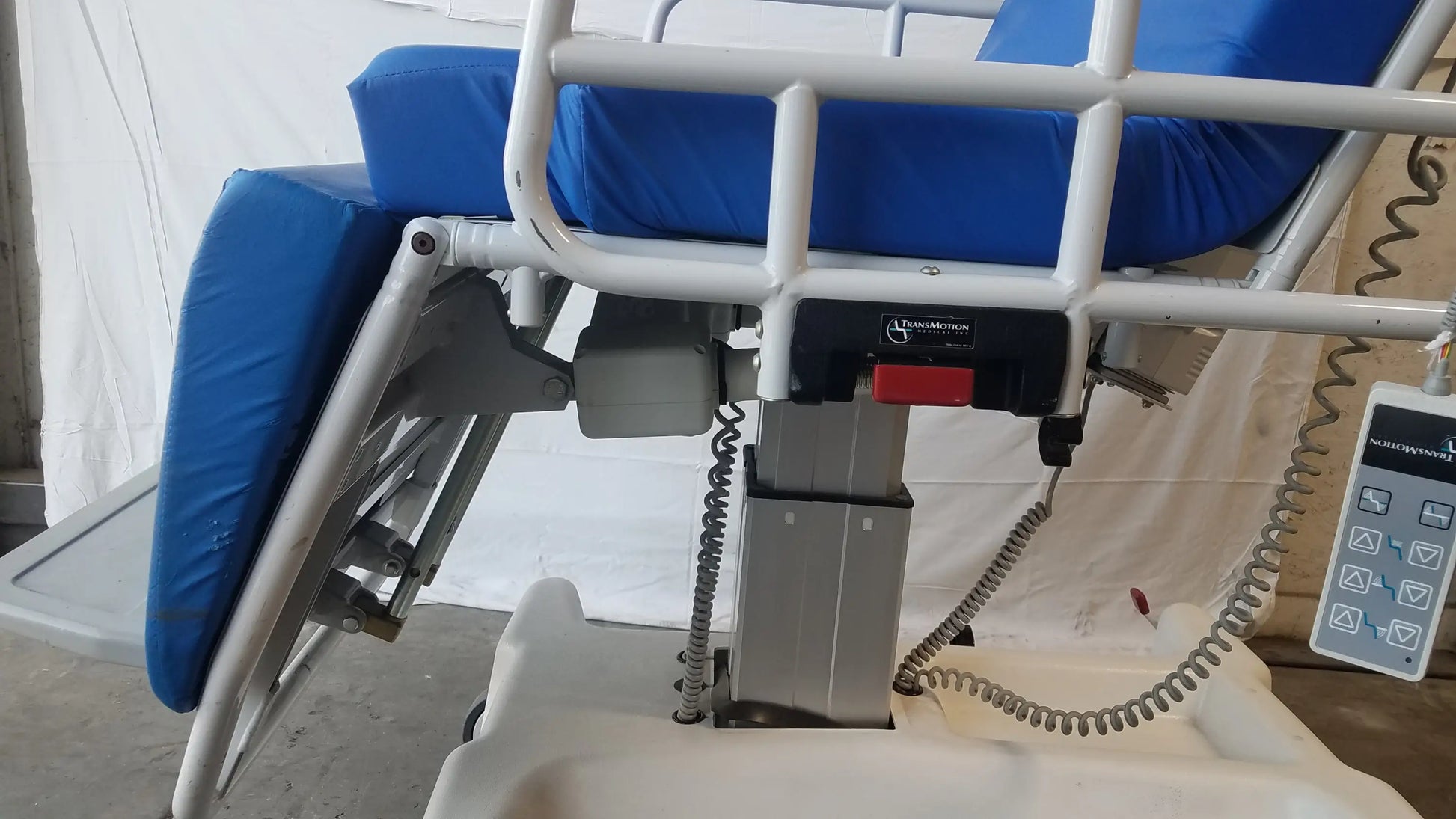 Blue cushioned multi purpose stretcher chair with white metal frame and control panel by TransMotion Medical TMM4