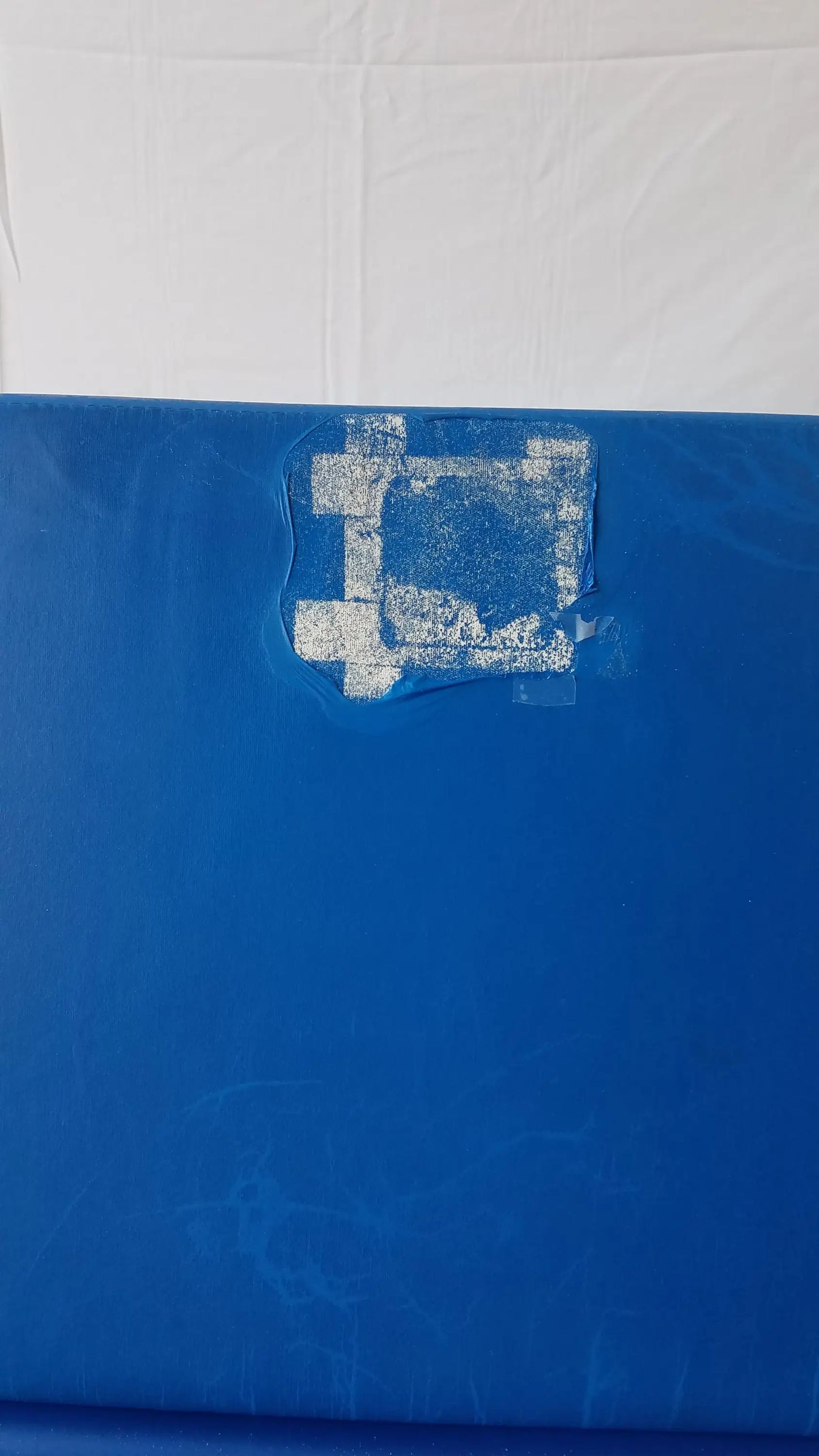 Blue plastic surface with white stencil design partially peeled on transmotion medical tmm4 multi purpose stretcher chair