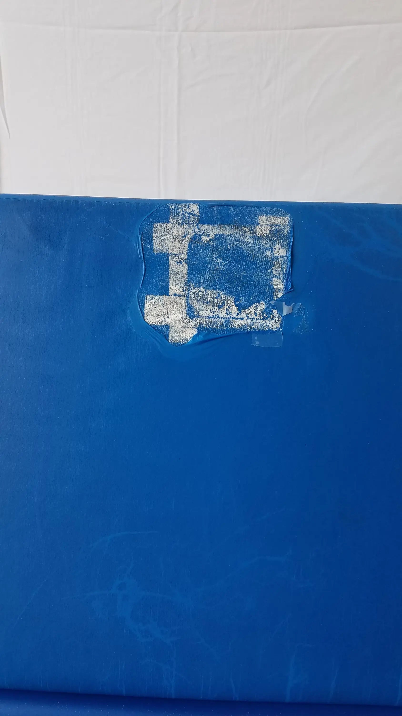 Blue plastic surface with white stencil design partially peeled on transmotion medical tmm4 multi purpose stretcher chair
