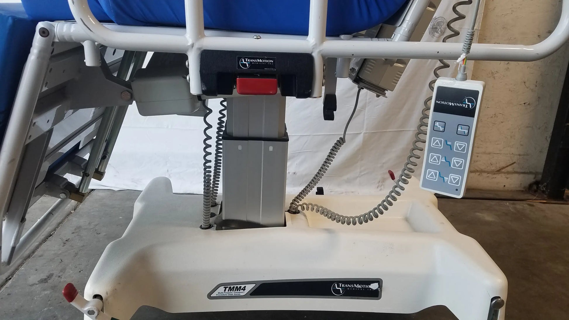 White plastic TransMotion Medical TMM4 multi purpose stretcher chair with blue cushion and control panel