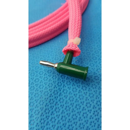 A green plastic t-shaped connector with a male plug attached to a pink braided reuse medical cable