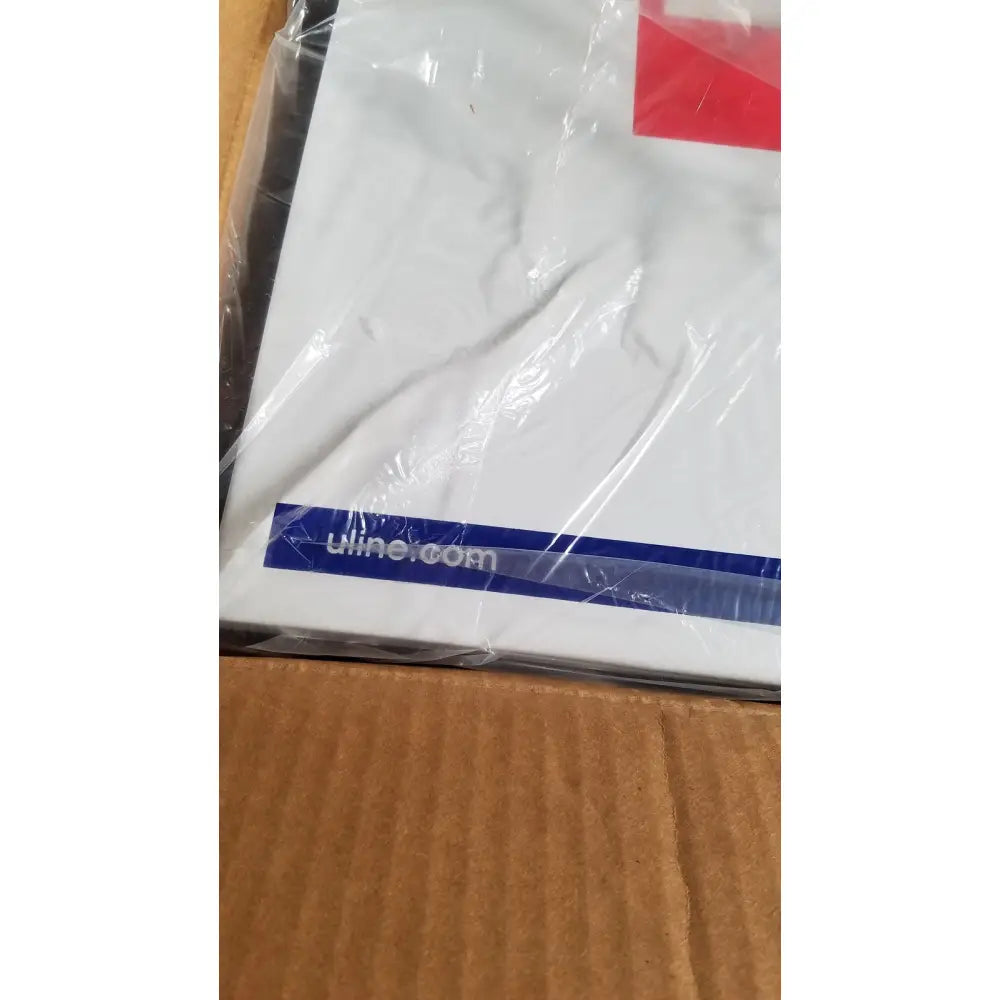 White t-shirt with red and blue logo wrapped in clear plastic alongside uline h-5951 3-shelf first aid cabinet