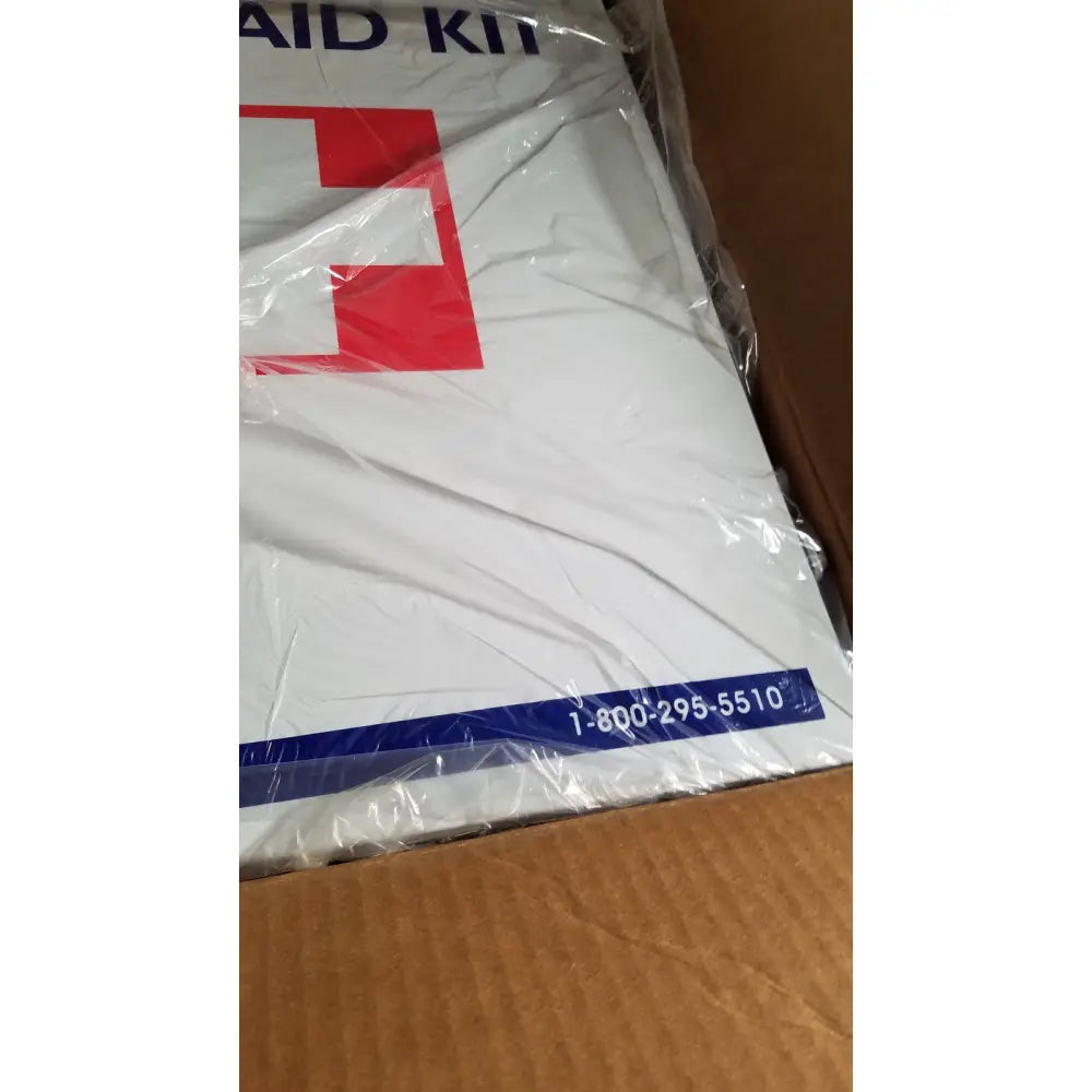 White first aid kit with red cross and blue text wrapped in plastic inside uline h-5951 3-shelf aid cabinet